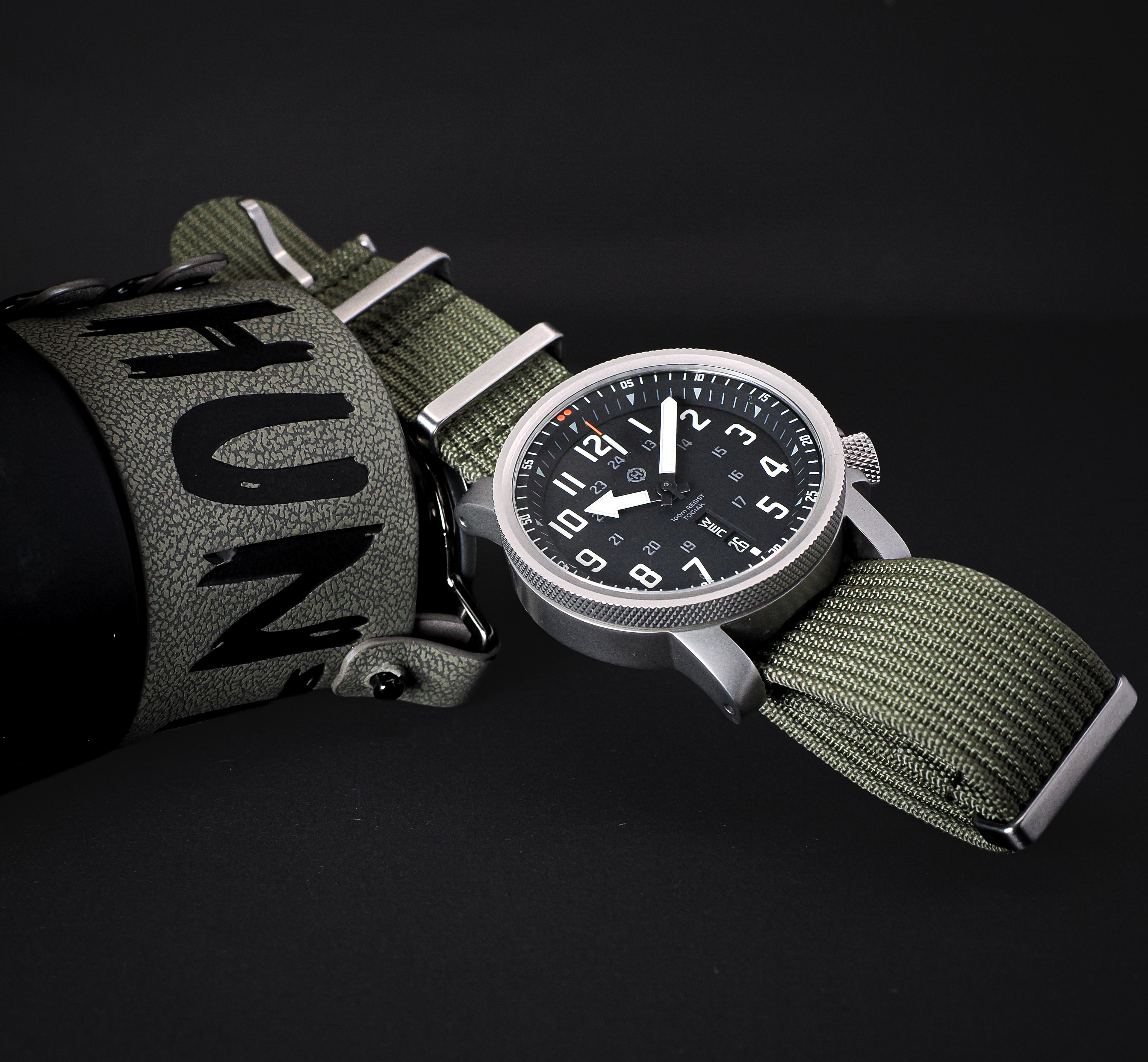 HELM Togiak Scout studio flat lay with olive nylon strap and outdoor equipment