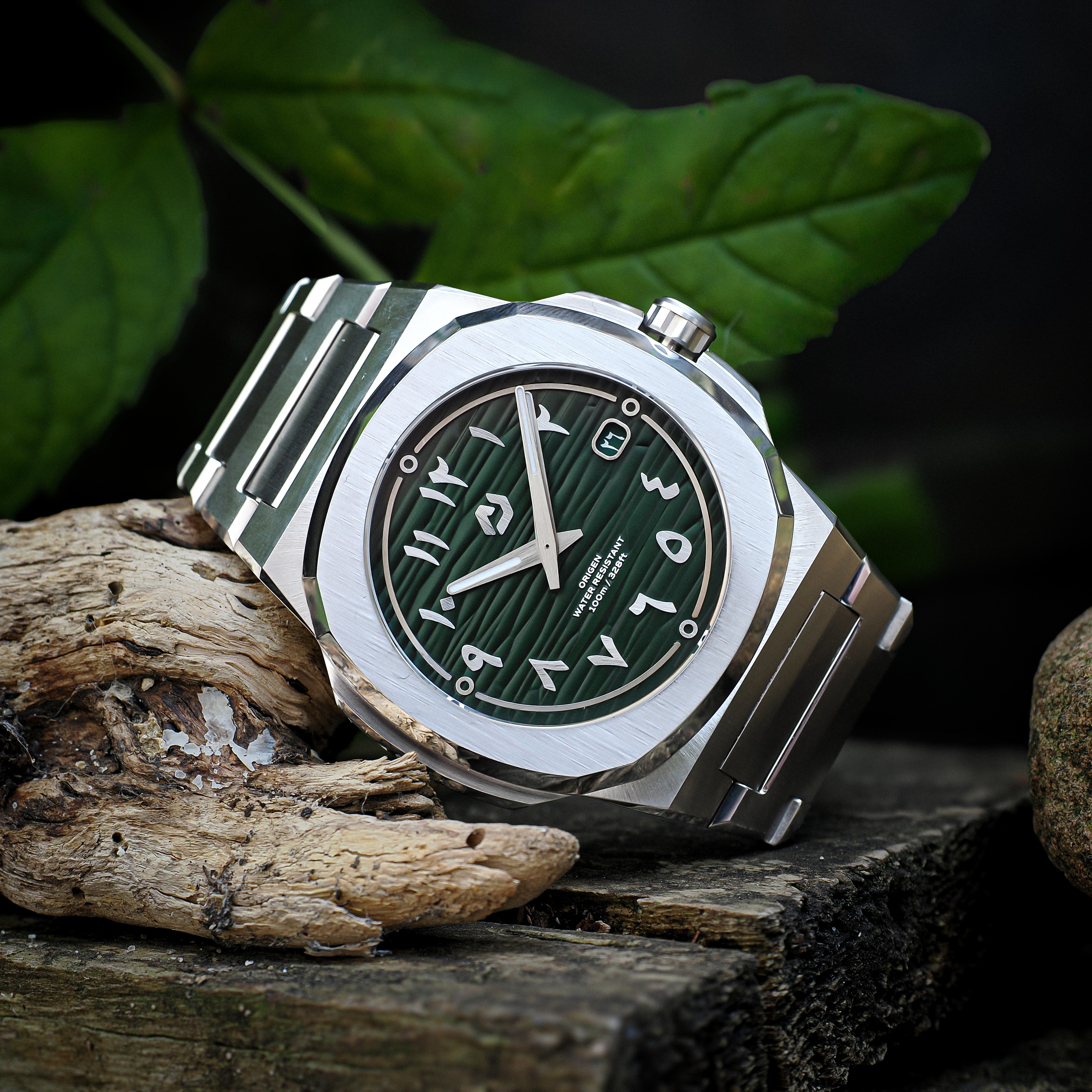 Nuncier Origen green dial watch photographed outdoors with wood and foliage