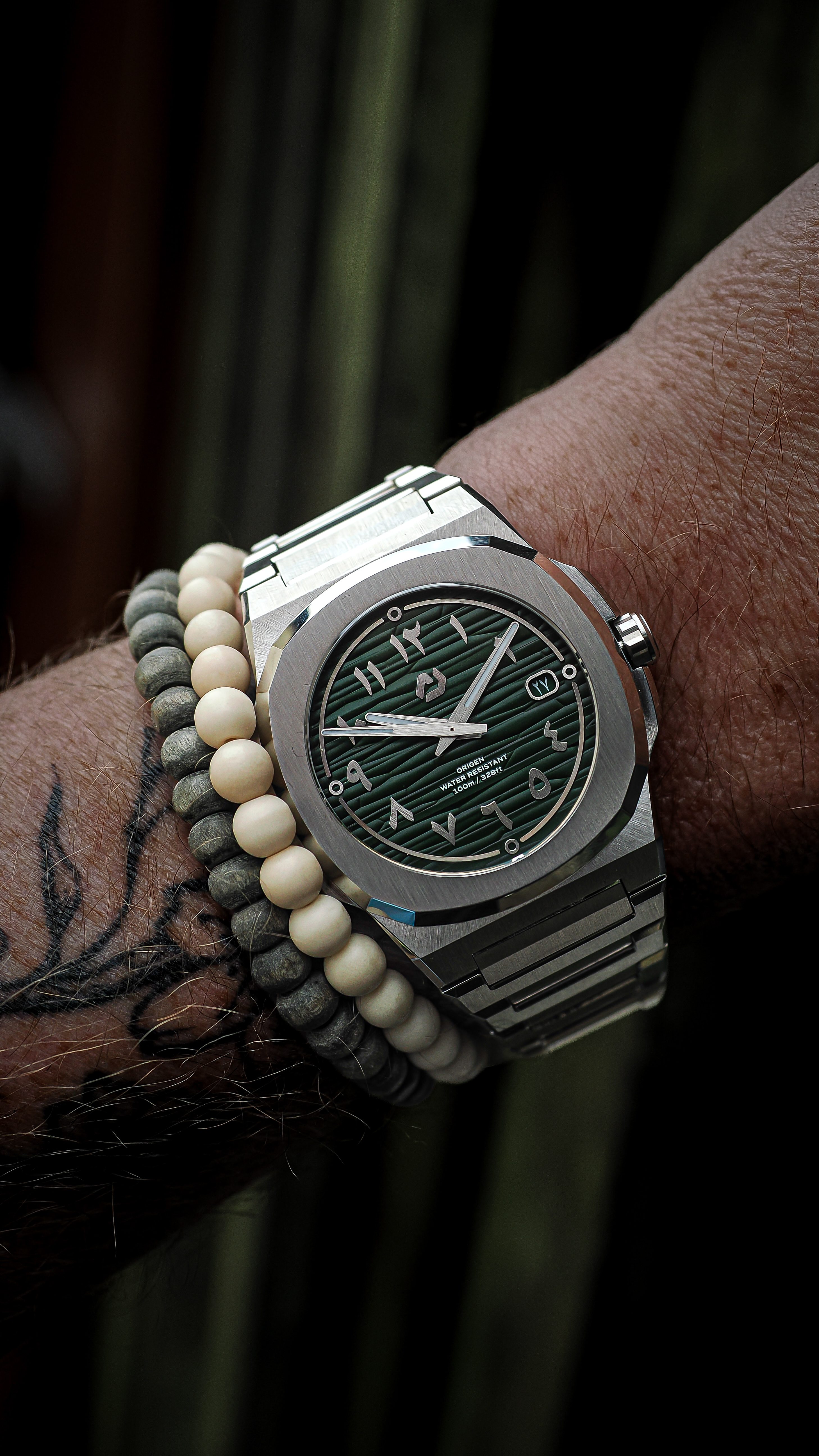 Nuncier Origen green dial integrated steel watch worn on the wrist